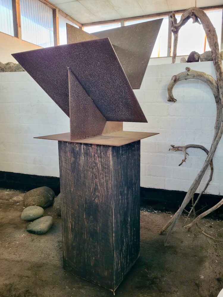 "Skulptur 'Schütte I' aus ineinander verschachtelten Metallflächen auf Holzsockel, im Atelier